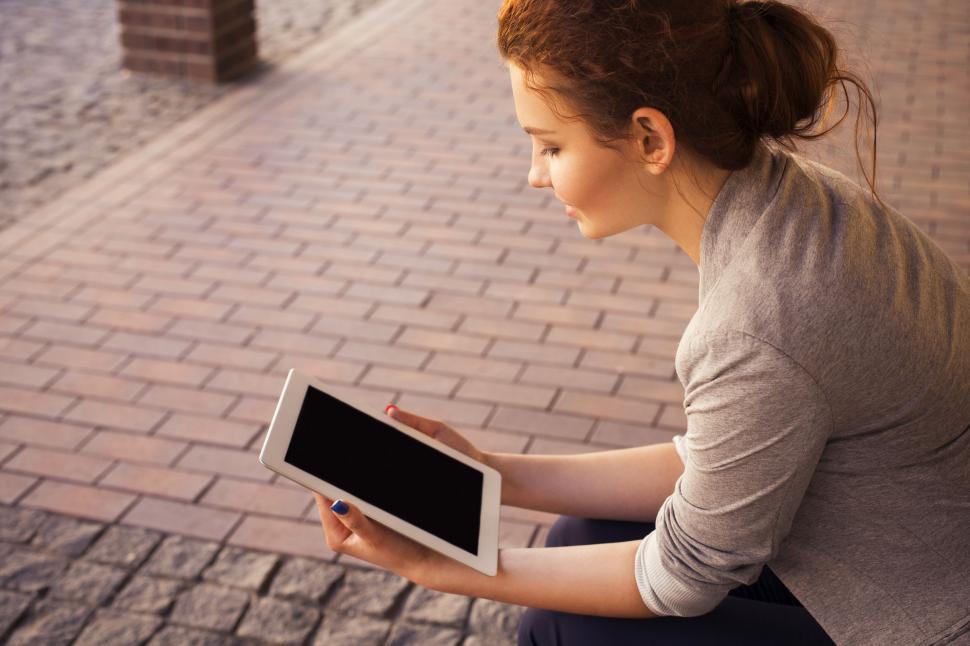 Free Image of Woman Sitting on Ground Holding Tablet 