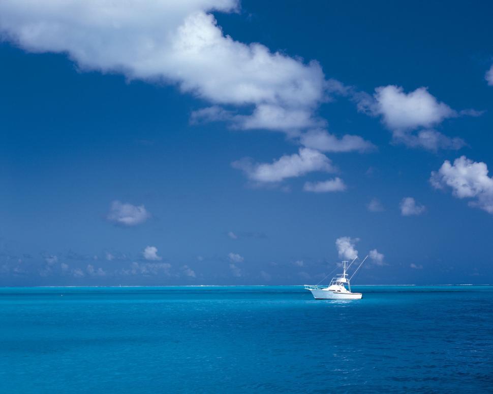 Free Image of Boat Sailing in Open Ocean Under Cloudy Blue Sky 