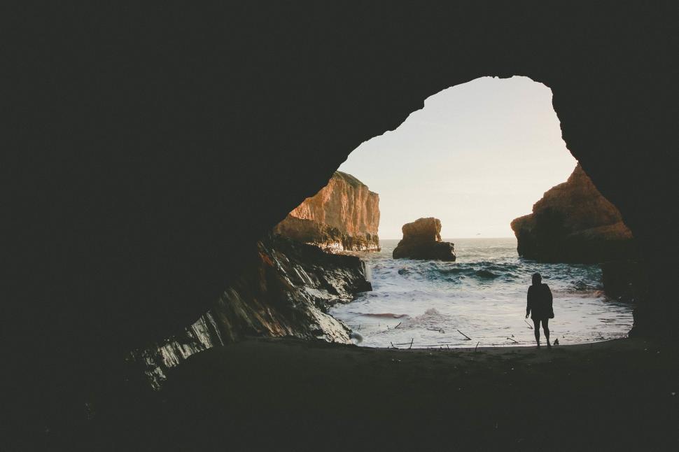 Free Image of Person Standing in Cave Looking Out at Ocean 