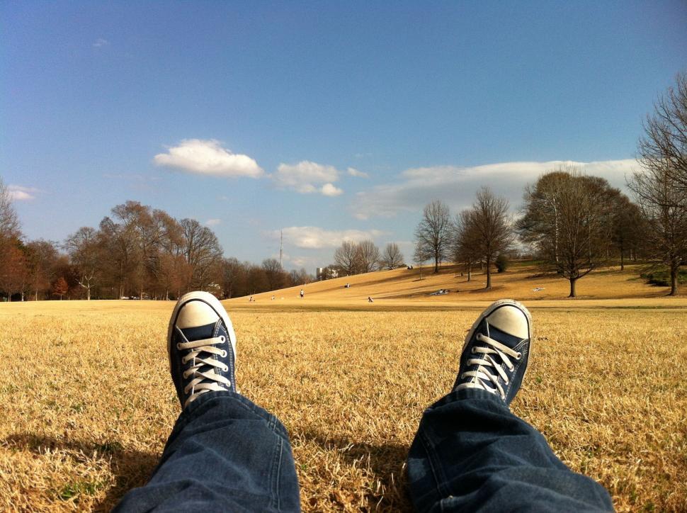 Free Image of Persons Feet Standing in Field With Trees in Background 