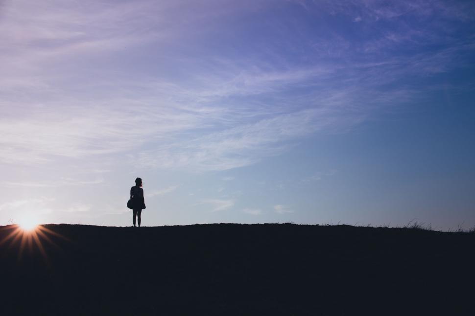 Free Image of Person Standing on Top of Hill Under Blue Sky 