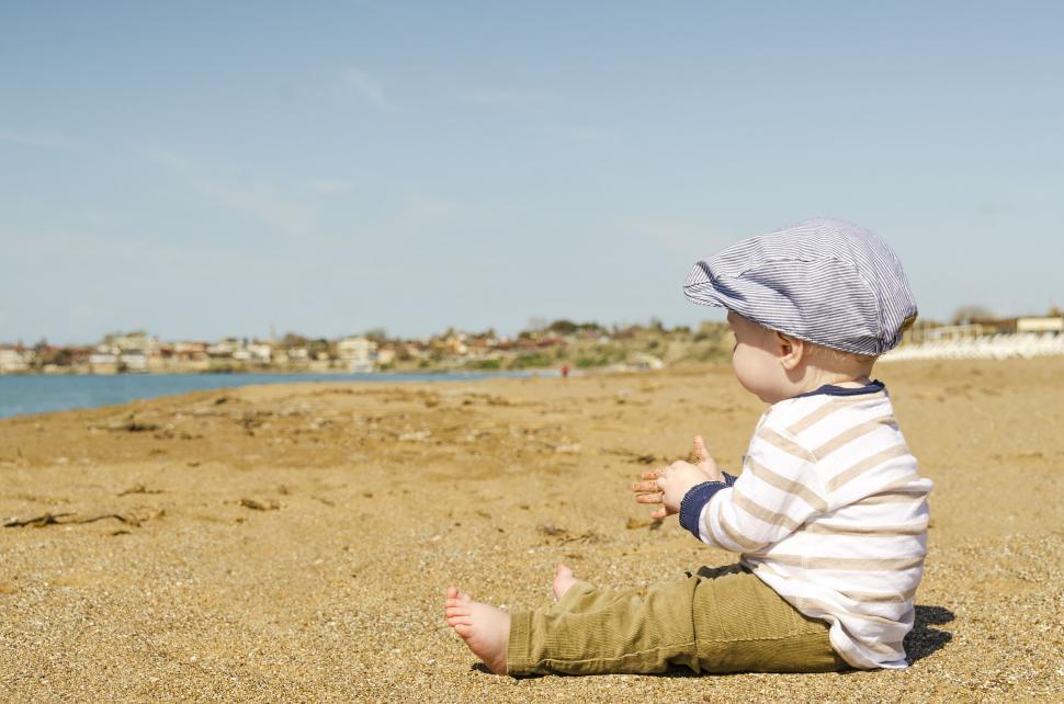 Free Image of Baby Sitting on Beach Looking at Water 