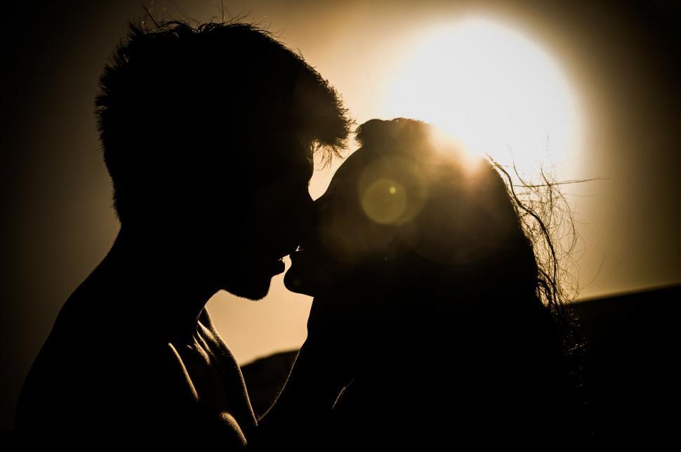 Free Image of Man and Woman Kissing in Front of the Sun 
