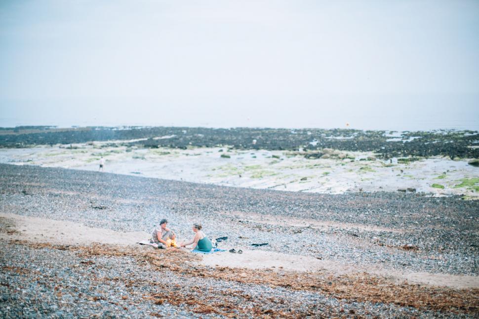 Free Image of Couple Sitting on Sandy Beach 