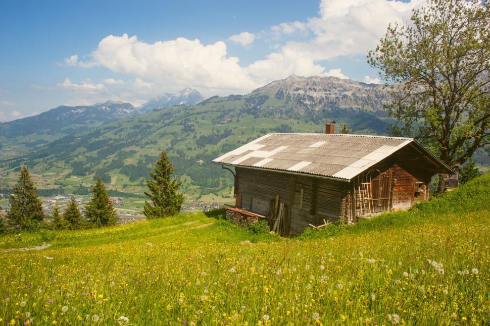 Free Image of Small Cabin in Field With Background Mountains 