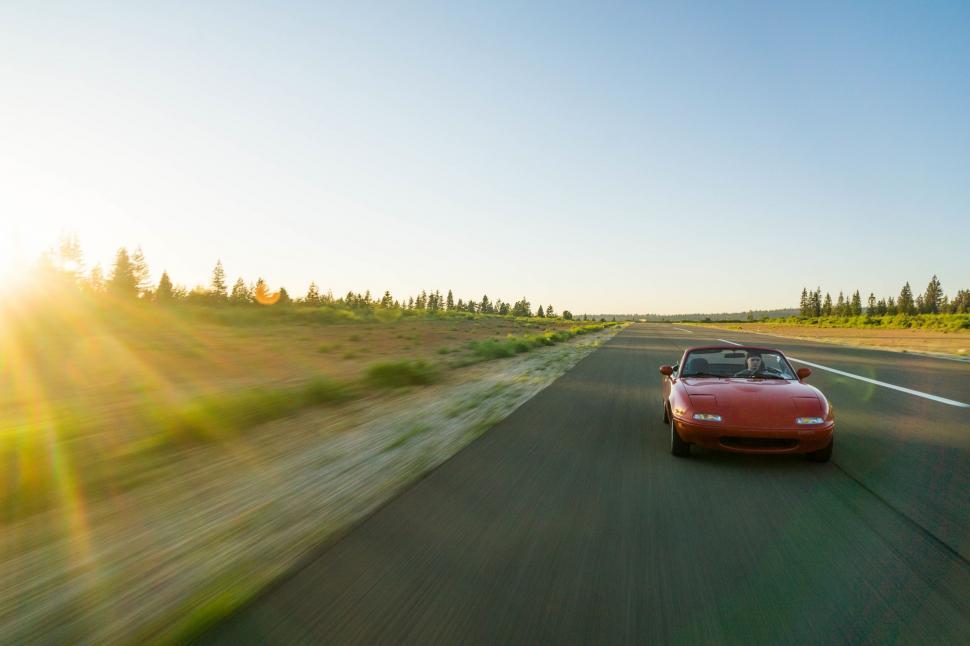 Free Image of Red Sports Car Driving Down Country Road 
