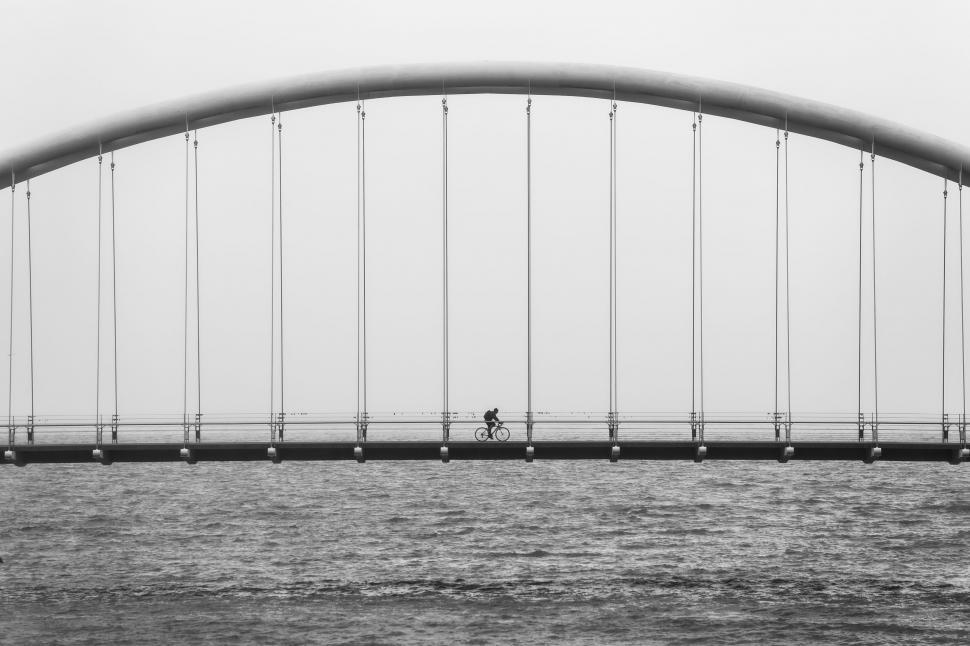 Free Image of Person Riding Bike Across Bridge Over Water 
