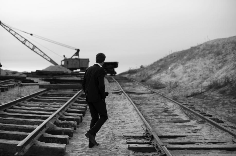 Free Image of Man Standing on Train Track Next to Crane 