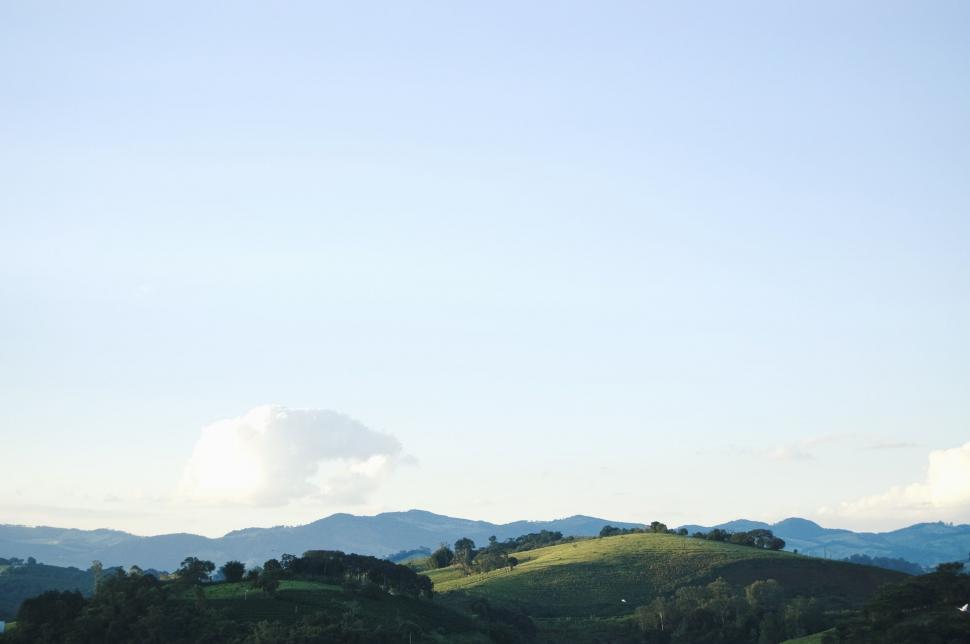 Free Image of Rolling Hill With Trees Amidst Background Hills 
