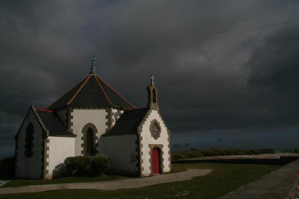 Free Image of White Church With Black Roof Under Cloudy Sky 