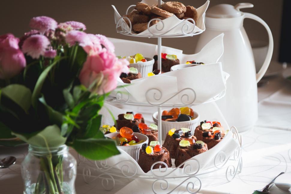 Free Image of Pink Flowers in Vase Next to Tiered Desserts 