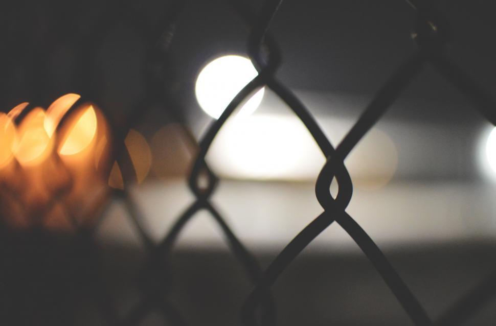 Free Image of Close Up of Fence With Lights in Background 