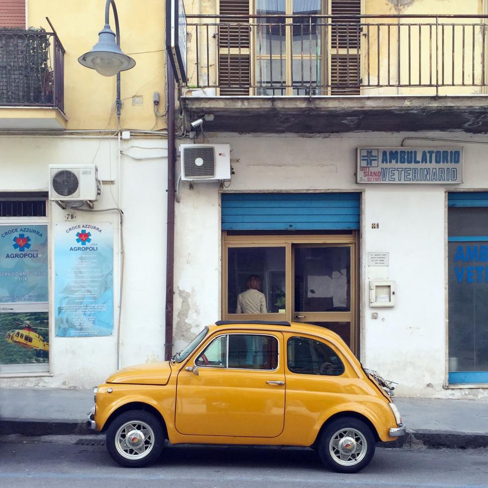 Free Image of Small Yellow Car Parked in Front of Building 