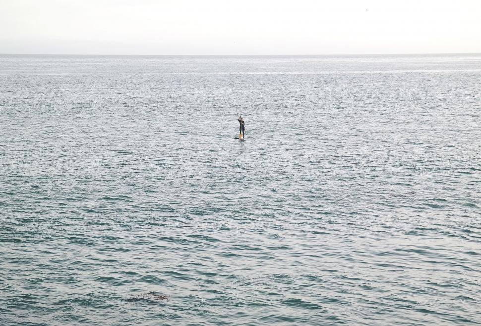 Free Image of Person Standing on Surfboard in Middle of Ocean 