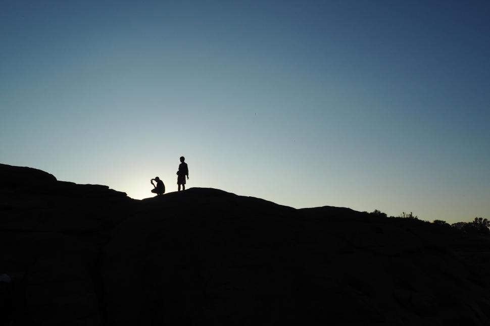 Free Image of Two People Silhouetted Standing on Hilltop 