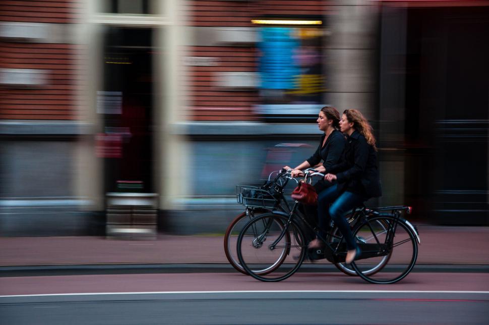 Free Image of Two Women Riding Bikes Down a Street 