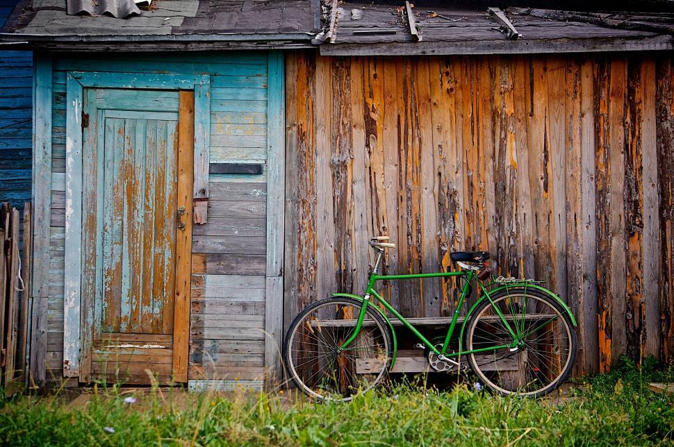 Free Image of Green Bike Parked in Front of Wooden Building 