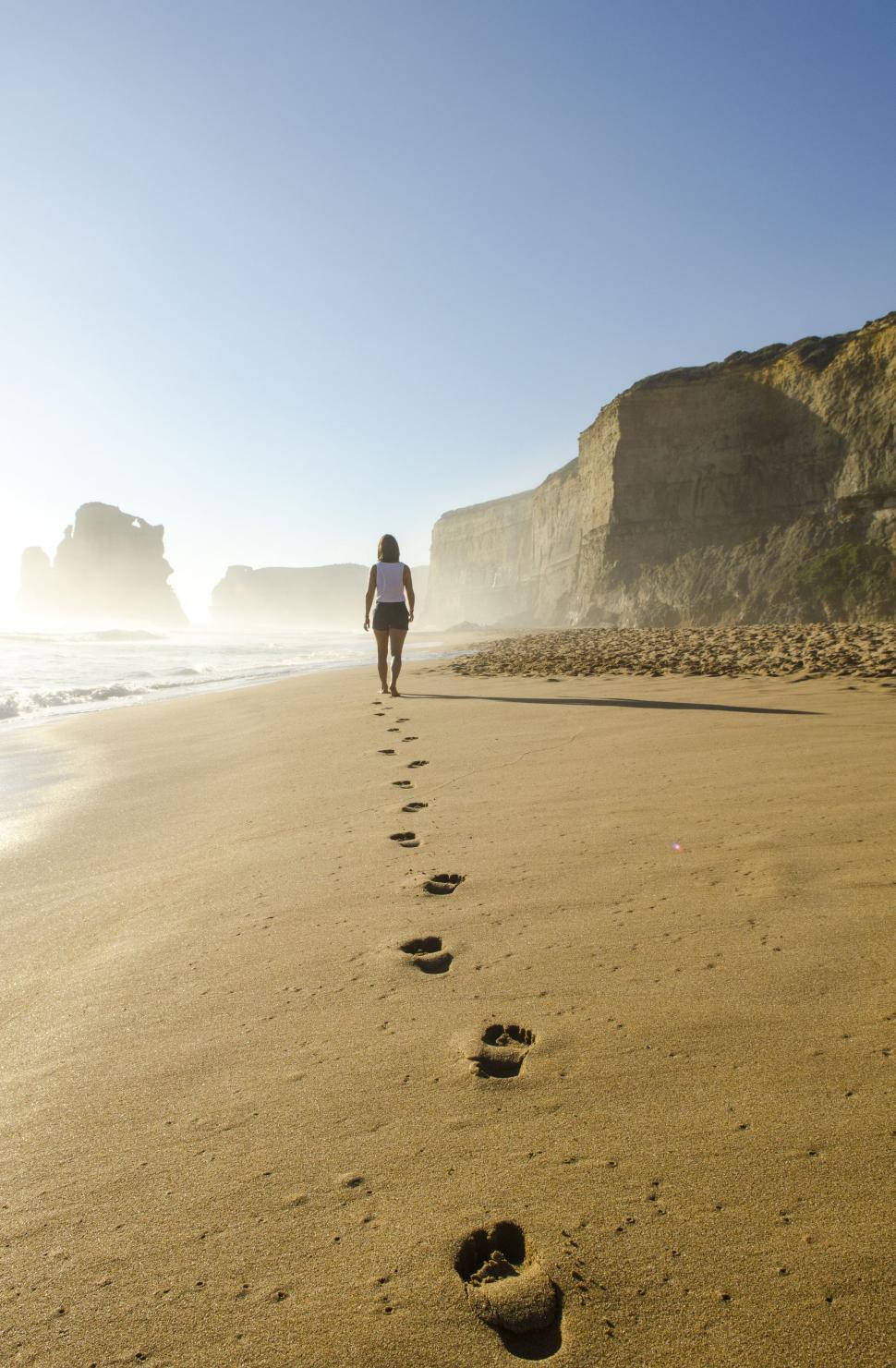Free Image of Person Walking on Beach With Footprints in Sand 