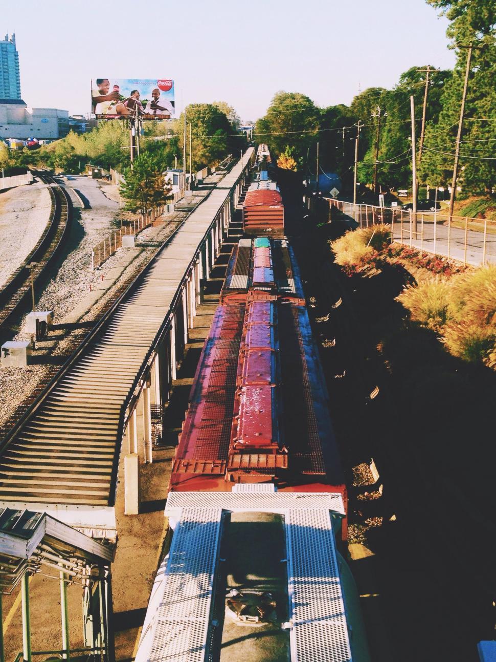 Free Image of Long Train Traveling Along Train Tracks Beside Forest 