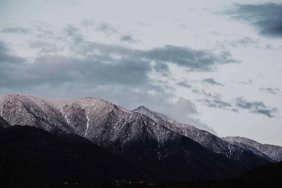 Free Image of Snow Covered Mountain Range Under Cloudy Sky 