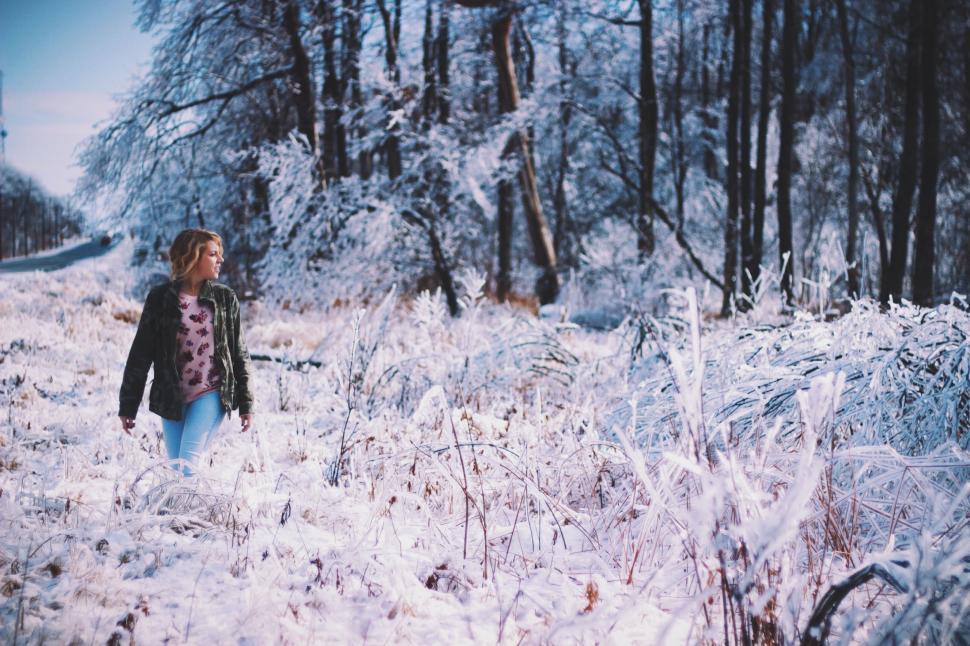 Free Image of Woman Walking Through a Snow Covered Forest 