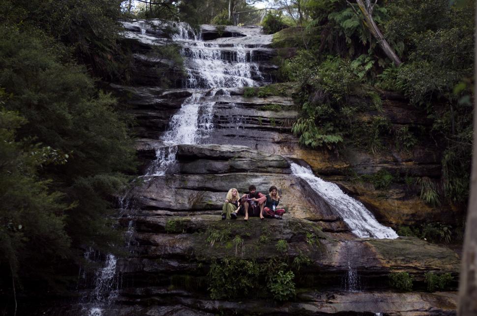 Free Image of Group of People Sitting at the Base of a Waterfall 