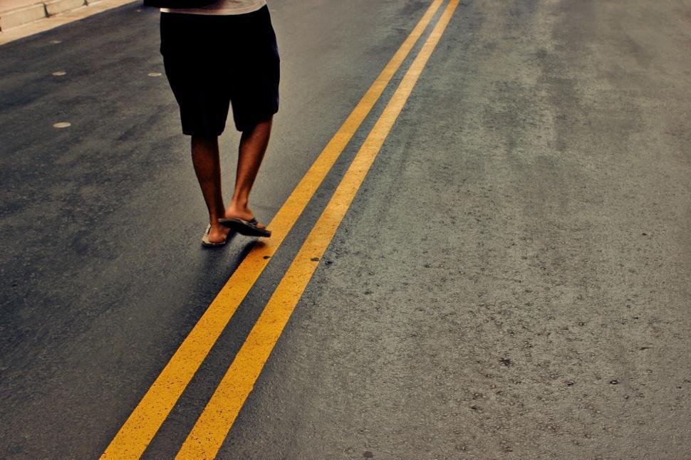 Free Image of Man Riding Skateboard Down Middle of Road 