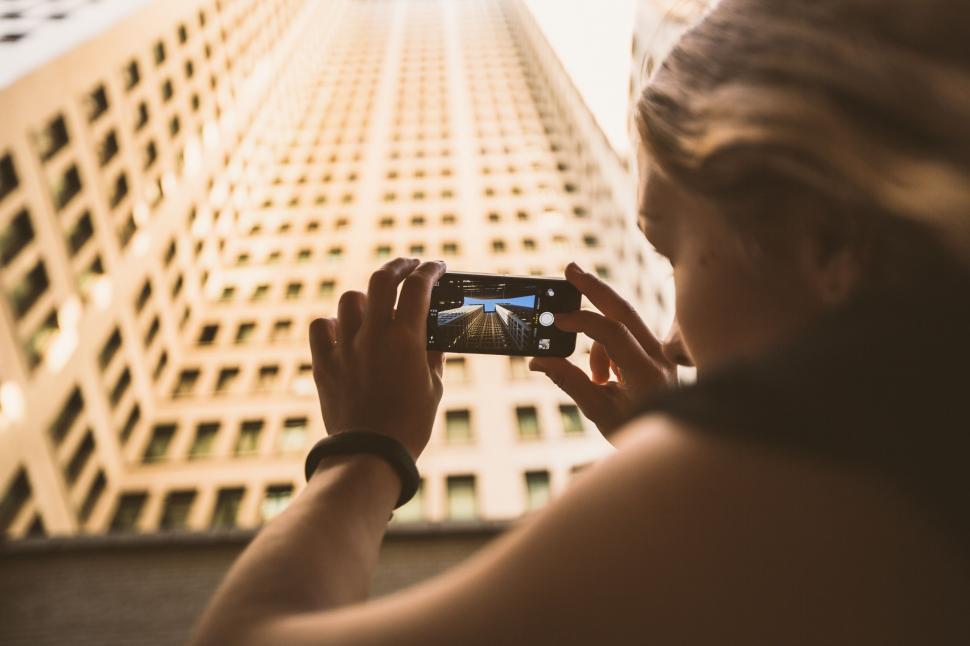 Free Image of Woman Capturing Image of Tall Building 