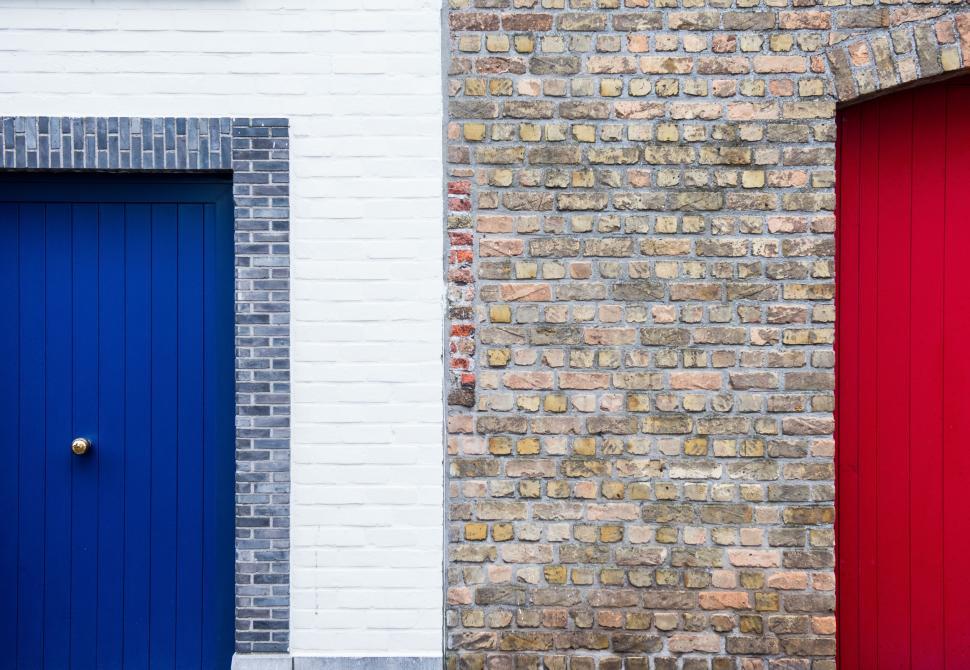Free Image of Two Red and Blue Doors in Front of a Brick Wall 