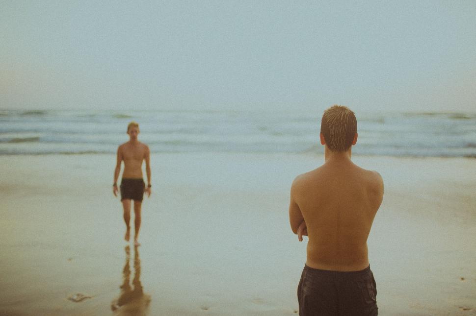 Free Image of Two Men Standing on Beach by Ocean 