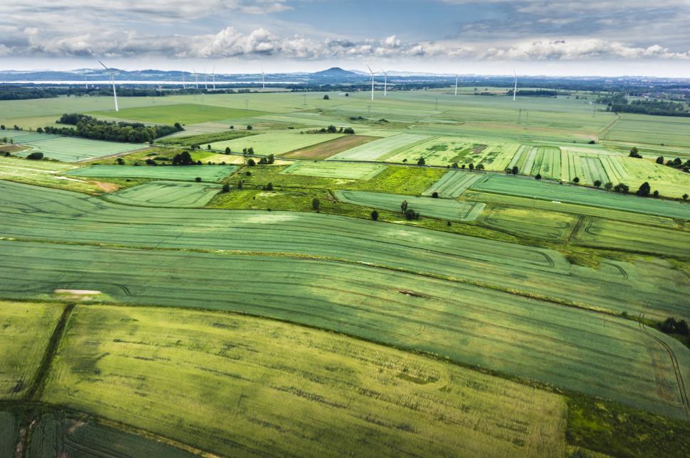 Free Image of Aerial View of Green Field With Wind Turbines in Distance 