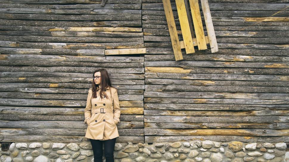 Free Image of Woman Standing in Front of Wooden Building 
