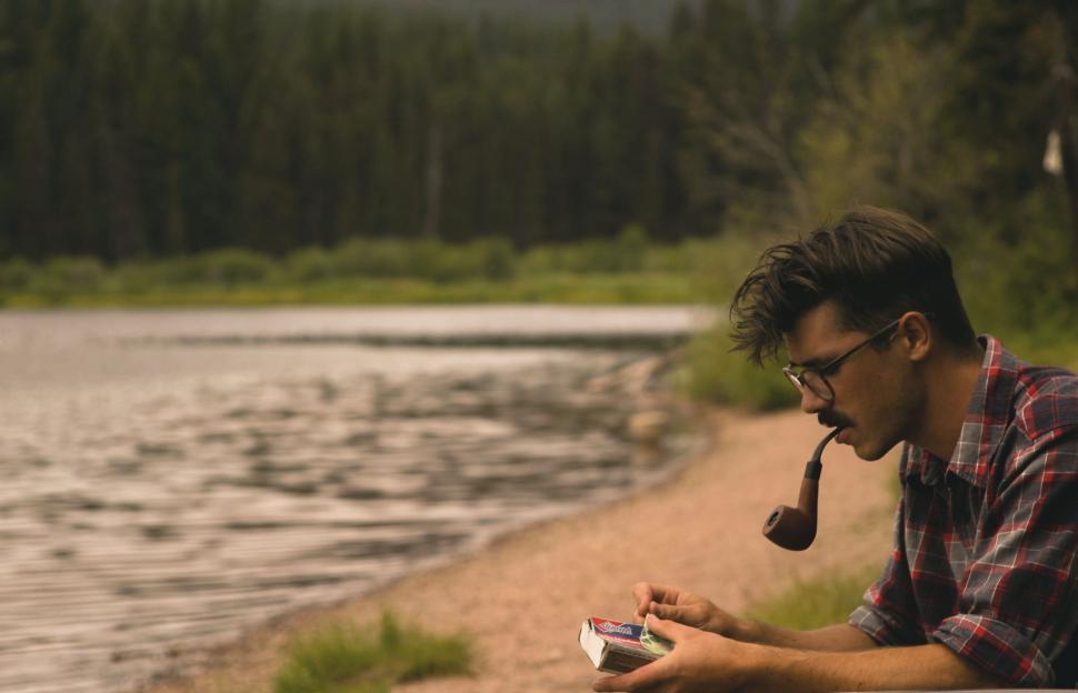 Free Image of Man Sitting by River With Pipe 