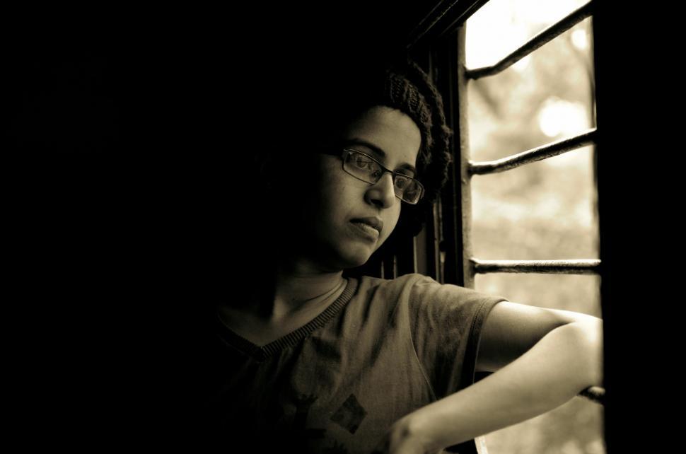 Free Image of Man With Glasses Leaning Against a Window 