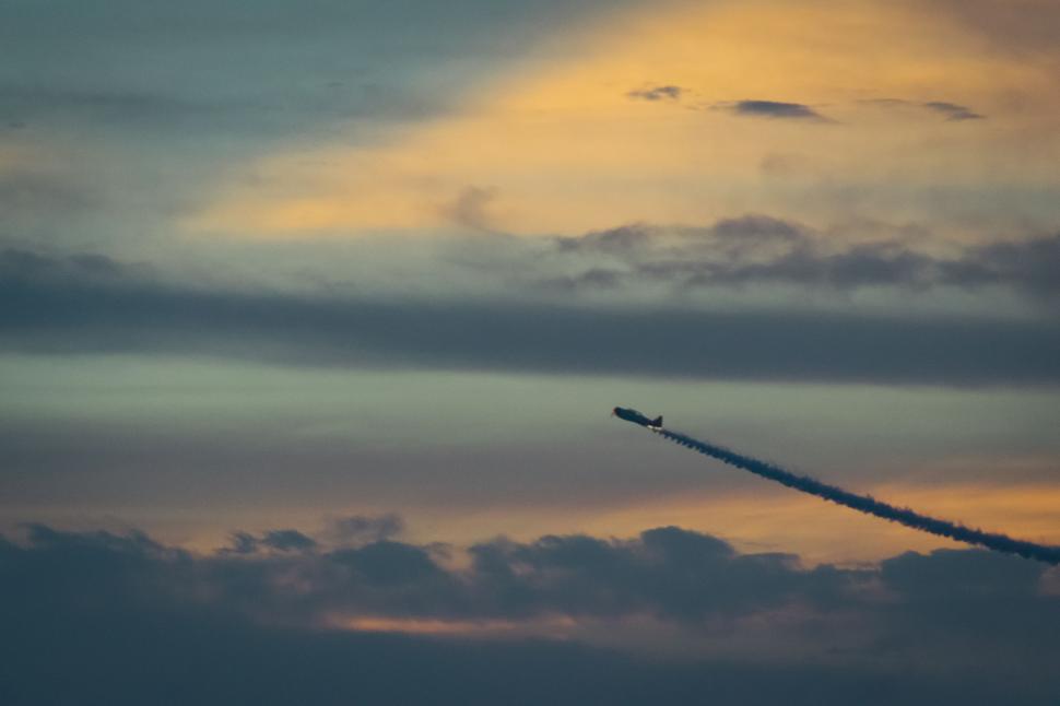 Free Image of Jet Flying Through Cloudy Sky at Sunset 