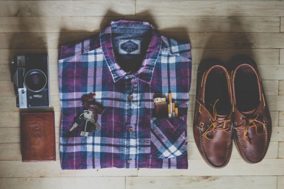 Free Image of Shoes, Camera, and Plaid Shirt Arranged on Table 