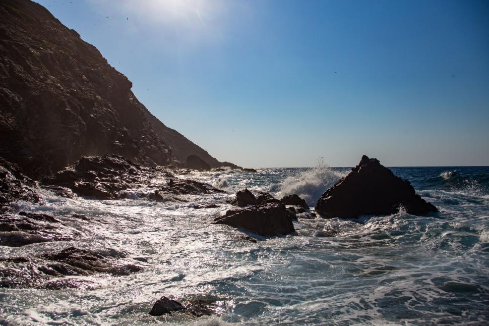 Free Image of Sun Shining Over Ocean and Rocks 