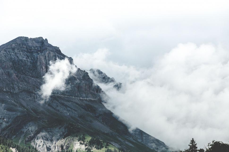 Free Image of Mountain Peak Covered in Clouds and Trees 