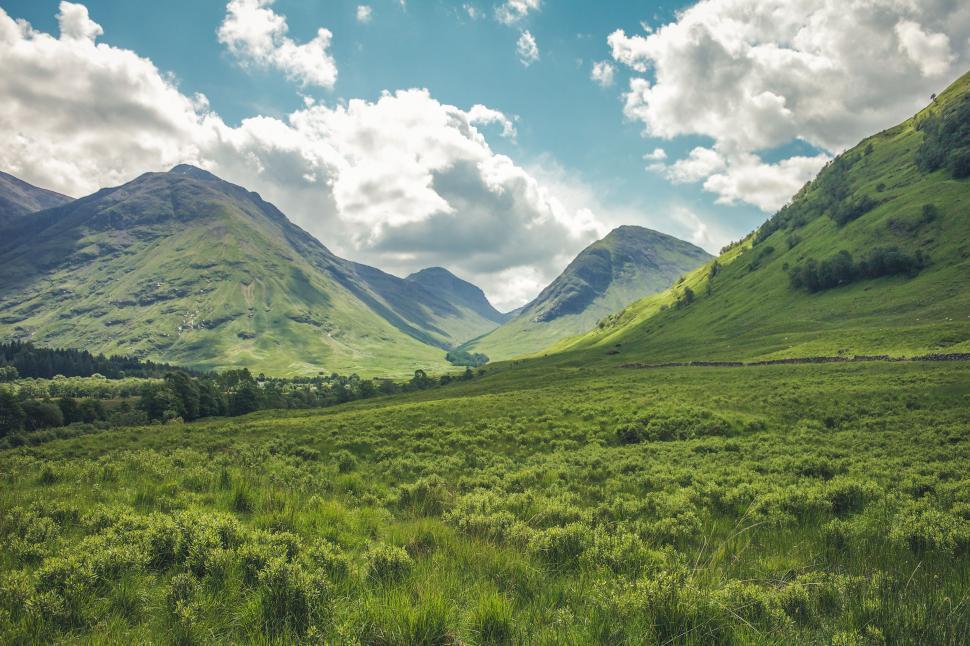 Free Image of Lush Green Field With Mountains in the Background 