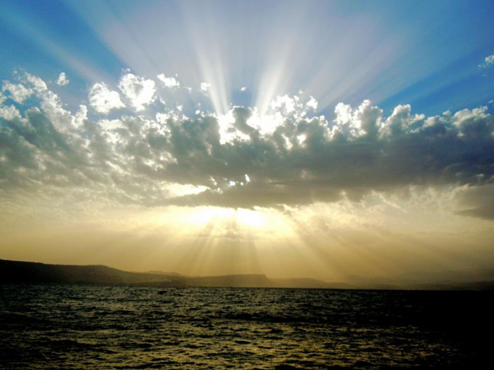 Free Image of Sun Shining Through Clouds Over Water 