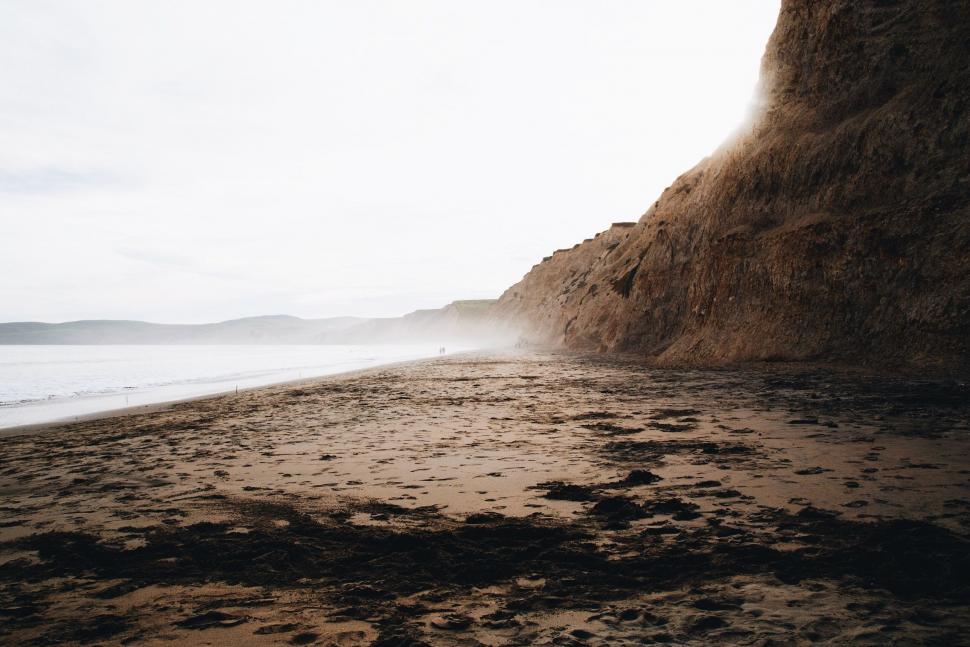 Free Image of Person Standing on Beach Next to Cliff 
