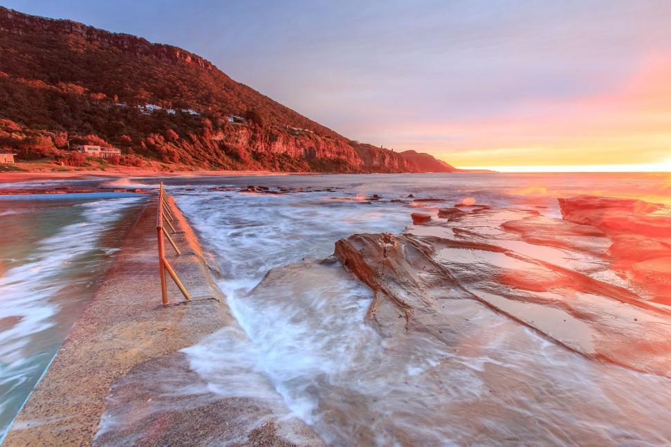Free Image of The Sun Sets Over a Rocky Beach 