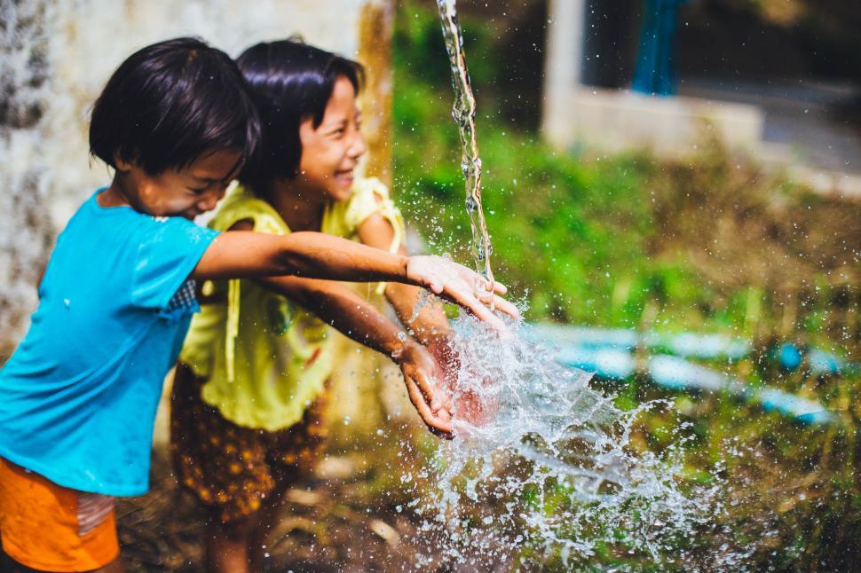 Free Image of Boy and Girl Playing With Water Hose 