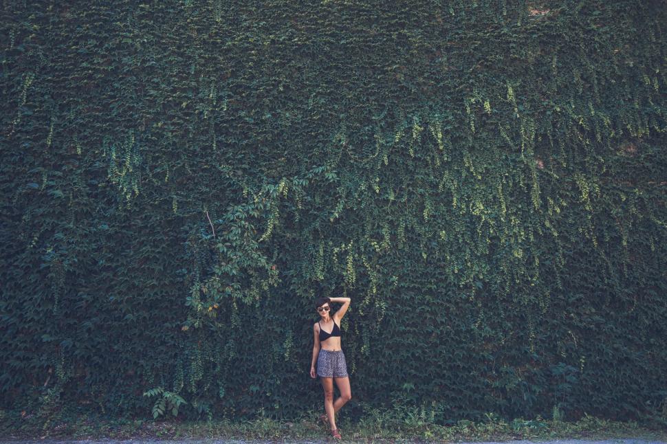 Free Image of Woman Standing in Front of Tall Green Wall 