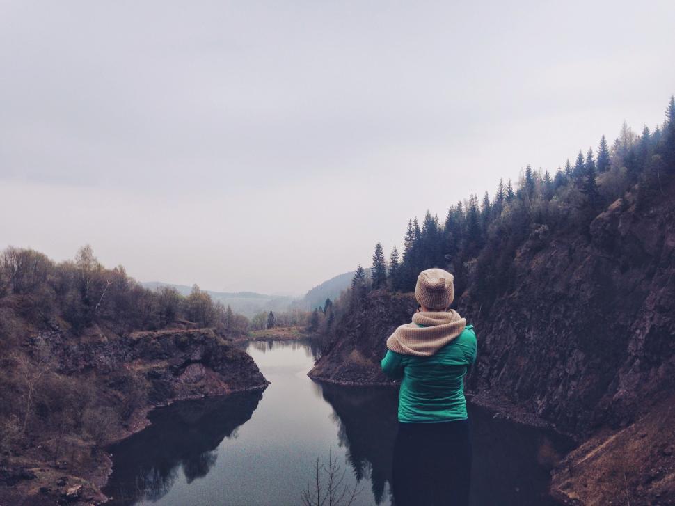 Free Image of Woman Standing on Cliff Overlooking River 