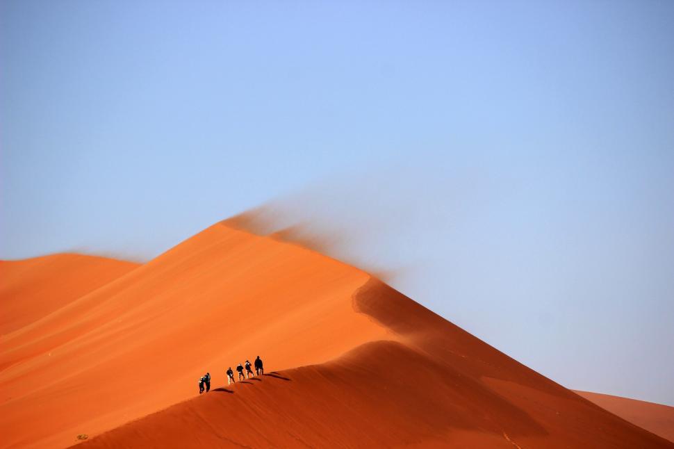 Free Image of Group of People Walking Up Sand Dune 
