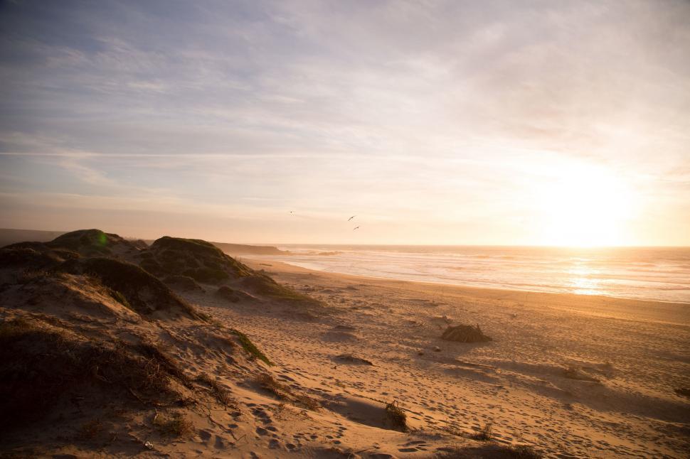 Free Image of The Sun Sets Over the Beach and Sand Dunes 