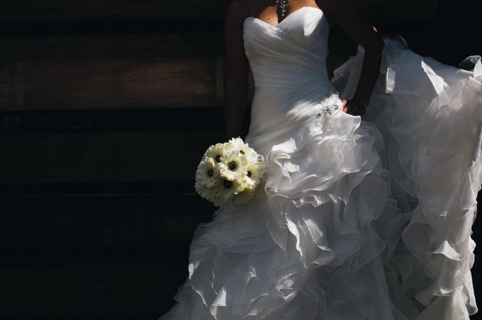 Free Image of Woman in Wedding Dress Holding Bouquet of Flowers 