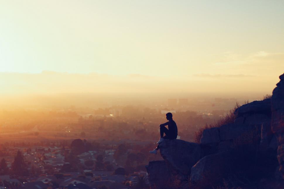 Free Image of Man Sitting on Cliff Overlooking City 
