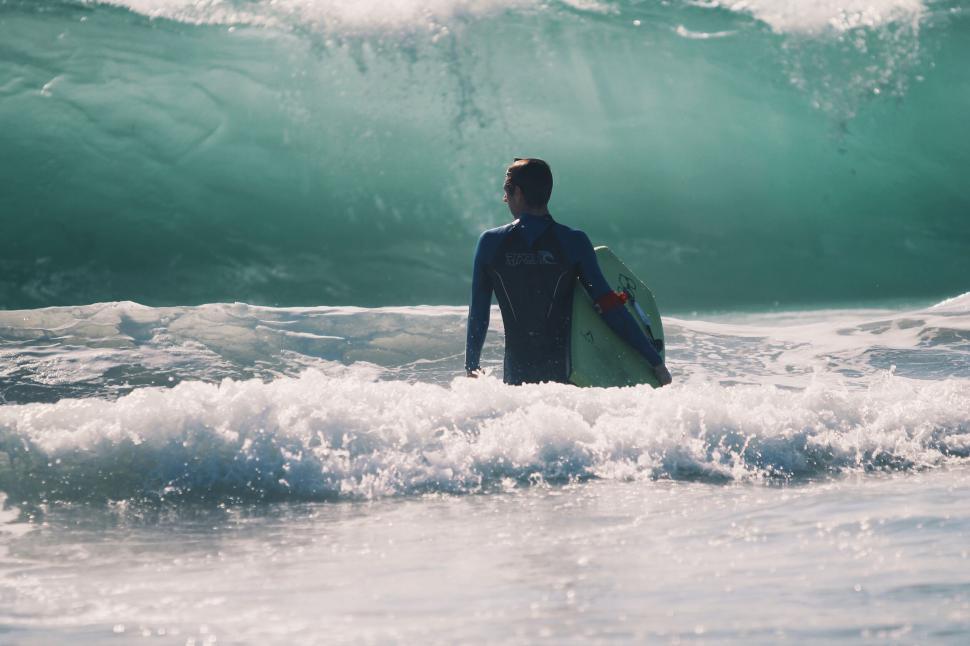 Free Image of Man Standing in Ocean With Surfboard 